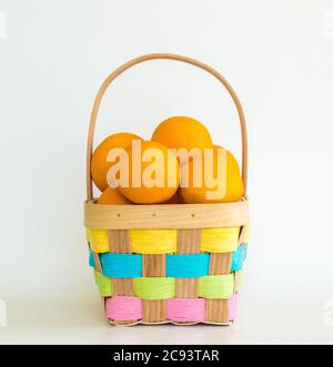 healthy Easter- colorful wicker Easter basket filled with ripe juicy oranges, isolated on white Stock Photo