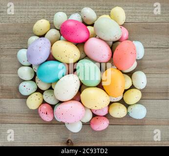 a jumbled pile of pastel colored speckled Easter eggs on a wood background Stock Photo