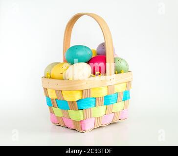 a wicker Easter basket filled with colorful speckled Easter eggs isolated on white Stock Photo