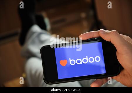 Badoo application on the smartphone in mans hand. Man laying and using application for dating and meeting. Social network concept, July 2020, Prague Stock Photo