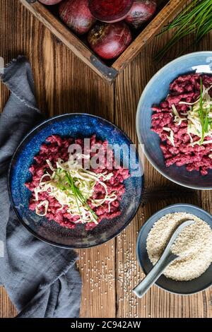 Flavorful boiled beetroot dumplings topped with hummus, smoked tofu and chives Stock Photo