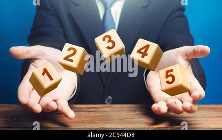 Man throws 5 numbered blocks with the numbers one two three four five from his hands. Five easy steps. Organization and systematization, step by instr Stock Photo