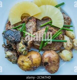 food meat with potatoes, onions, artichoke and chives and pineapple on withe plate top view Stock Photo