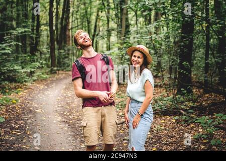 Young caucasian couple uses a smartphone to navigate in the forest. Hiking tourists orientation on the terrain using an online map, an application in Stock Photo