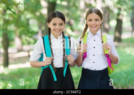 Playful mood. Fashion little girls with backpack in park. children with backpack smiling. students outside in summer park smiling happy. girls with school bags. child with backpack. happy time. Stock Photo