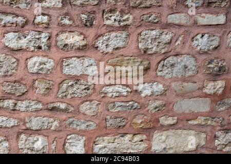 Gray stone wall texture with lime bricks pasted with red colored cement. Stock Photo