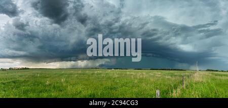 Panorama of a massive mesocyclone weather supercell, which is a pre-tornado stage, passes over a grassy part of the Great Plains Stock Photo