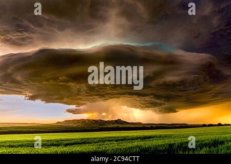 Panorama of a massive mesocyclone weather supercell, which is a pre-tornado stage, passes over a grassy part of the Great Plains while fiercely trying Stock Photo