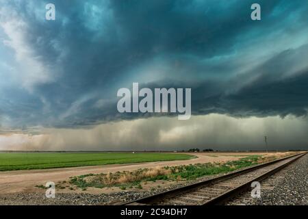 Panorama of a massive mesocyclone weather supercell, which is a pre-tornado stage, passes over a grassy part of the Great Plains while fiercely trying Stock Photo