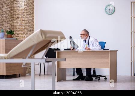 Old experienced doctor working in the clinic Stock Photo