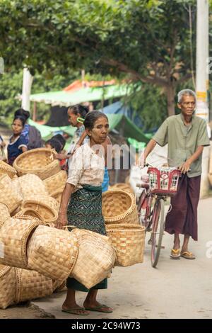 Sagaing/Myanmar-October 3rd 2019: A Burmese elderly wicker vendor carrying baskets made of bamboo in the market. Stock Photo