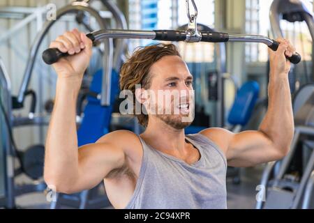 Shoulder pull down machine. Fitness man working out lat pulldown training at gym. Upper body strength exercise for the upper back Stock Photo