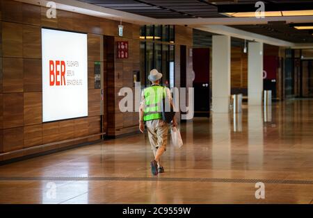 28 July 2020, Brandenburg, Schönefeld: An extra in a green high-visibility vest passes through the terminal after the security check at the Capital Airport Berlin-Brandenburg (BER). In the second phase of the Operational Readyness and Airport Transfer (ORAT), some 500 to 600 employees and 400 volunteers rehearsed standard passenger processes from check-in to security control, boarding and deboarding (arrival). Photo: Soeren Stache/dpa-Zentralbild/dpa Stock Photo