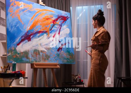 Happy artist in art studio after creating a masterpiece on large canvas. Modern artwork paint on canvas, creative, contemporary and successful fine art artist drawing masterpiece Stock Photo