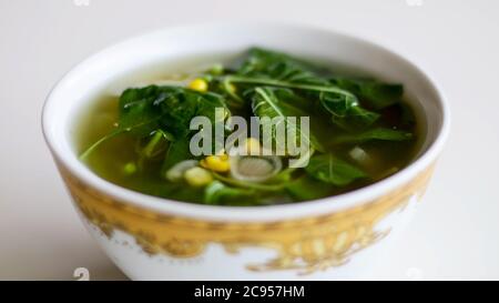 Sayur Bening Bayam or Spinach Clear Soup on white background. Boiled spinach with corn. Indonesian food. Stock Photo