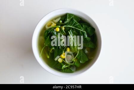 Sayur Bening Bayam or Spinach Clear Soup on white background. Boiled spinach with corn. Indonesian food. Stock Photo