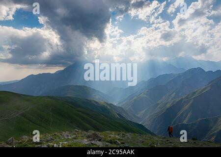 Idyllic summer landscape with hiking trail in the mountains with beautiful fresh green mountain pastures, blue sky and clouds. Tian-Shan, Kyrgyzstan. Stock Photo