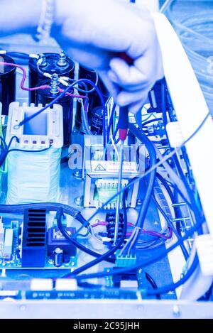 Hands of an Technician holding a screwdriver as he fixes an electronics device Stock Photo