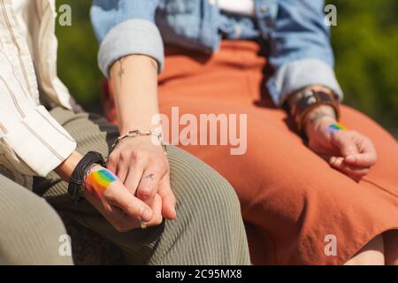 Close-up of two young girlfriends holding hands while sitting outdoors Stock Photo