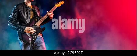 Guitar player performs on stage. Rock guitarist plays solo on an electric guitar. Artist and musician performs like rockstar. Stock Photo