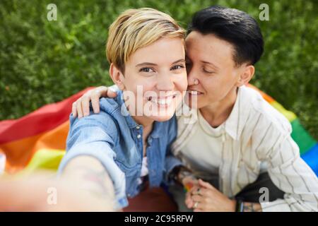 Portrait of young woman with short blonde hair smiling at camera while taking selfie portrait with her girlfriend outdoors Stock Photo