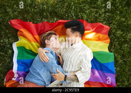 High angle view of two lesbians lying on colored flag and embracing during picnic in the park Stock Photo