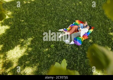 Two lesbians lying on green grass and enjoying each other outdoors in the park Stock Photo