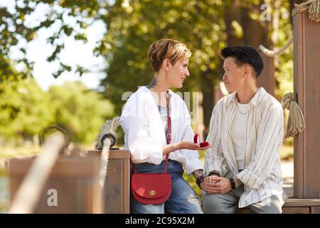 Young woman making proposal to her girlfriend while they sitting in the park Stock Photo