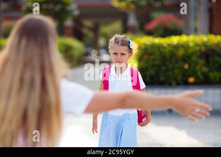 Mother and kids after school. Young mom picking up children after lessons in kindergarten or preschool. Pick up students. Boy and girl running to pare Stock Photo