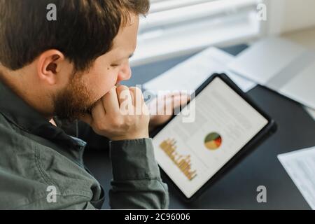 Closeup financier using tablet and looking at graphs with diagrams on screen. Stock Photo