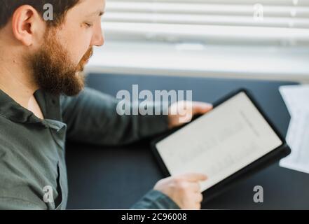 Serious male executive using digital tablet and reading news. Stock Photo