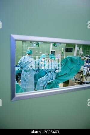 Essen, North Rhine-Westphalia, Germany - Hospital. View through a window into an operating theatre. A surgical team is working on a foot operation.  - Stock Photo