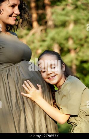 the daughter hugs the pregnant mother and waits for the appearance of her sister. Stock Photo