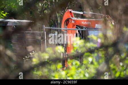 Seelze, Germany. 29th July, 2020. An excavator is standing in an allotment garden in the Hanover region during a police operation. In the case of the missing little Maddie McCann, police are continuing the excavation work in an allotment garden near Hanover. Credit: Julian Stratenschulte/dpa/Alamy Live News Stock Photo