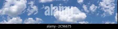 Panorama of diffuse white, puffy clouds against a clear blue sky background, creative copy space, horizontal aspect Stock Photo