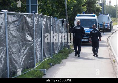 Seelze, Germany. 29th July, 2020. Policemen walk along privacy fences at an allotment garden in the Hannover region. In the case of the missing little Maddie McCann, police are continuing the excavation work in an allotment garden near Hanover. Credit: Julian Stratenschulte/dpa/Alamy Live News Stock Photo
