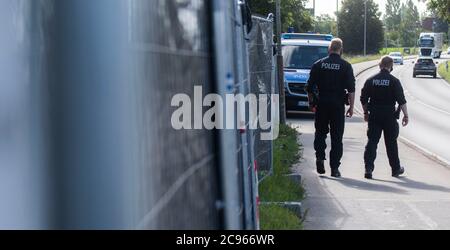 Seelze, Germany. 29th July, 2020. Policemen walk along privacy fences at an allotment garden in the Hannover region. In the case of the missing little Maddie McCann, police are continuing the excavation work in an allotment garden near Hanover. Credit: Julian Stratenschulte/dpa/Alamy Live News Stock Photo