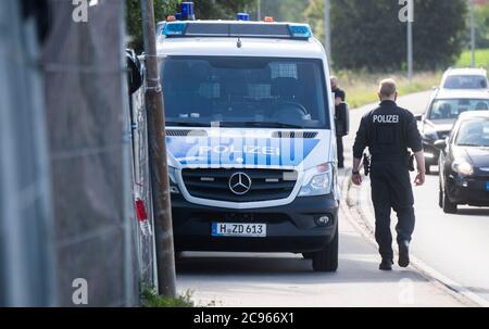 Seelze, Germany. 29th July, 2020. A policeman walks along privacy fences at an allotment garden in the Hannover region. In the case of the missing little Maddie McCann, police are continuing the excavation work in an allotment garden near Hanover. Credit: Julian Stratenschulte/dpa/Alamy Live News Stock Photo
