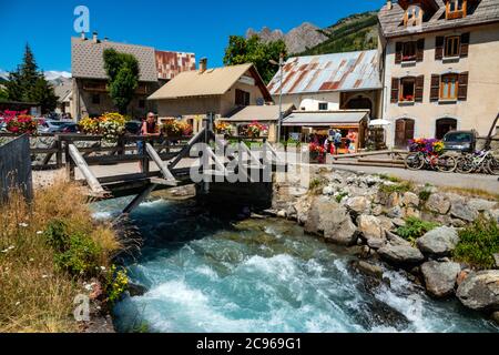 Wooden bridge over the Guisane river, and old houses in the small village of Le Casset, Serre Chevalier, near Briancon, Ecrins, France Stock Photo