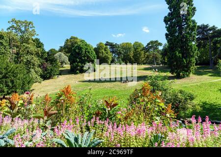 People on the grass in Buttes-Chaumont park - Paris, France Stock Photo