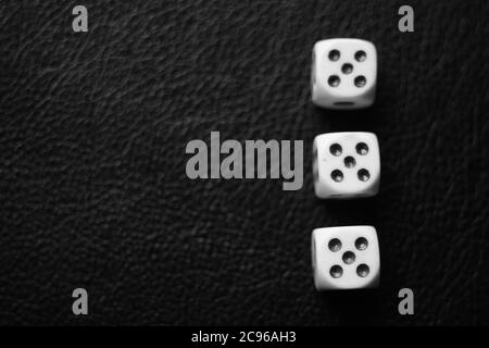 Three dice with fives on a black leather table. Bw photo. Top view. Stock Photo