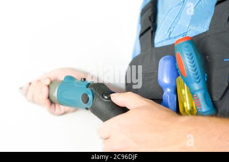 worker holds an electric screwdriver and a screw in his hand Stock Photo