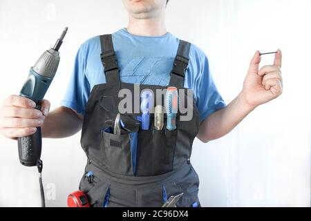 worker holds an electric screwdriver and a screw in his hand Stock Photo
