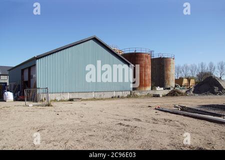 Old rusty silos, a green shed and a sand pile. Alkmaar, Netherlands, March Stock Photo