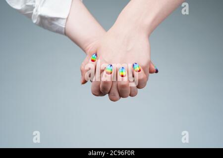 Image of woman with rainbow manicure holding hand with other woman Stock Photo