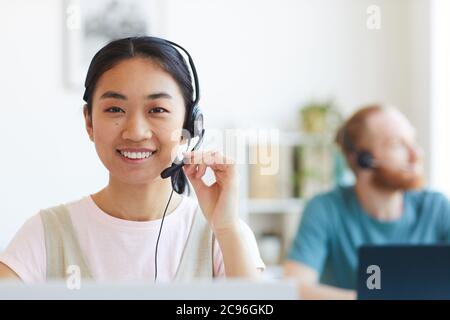 Portrait of happy smiling female customer support phone operator at workplace Stock Photo