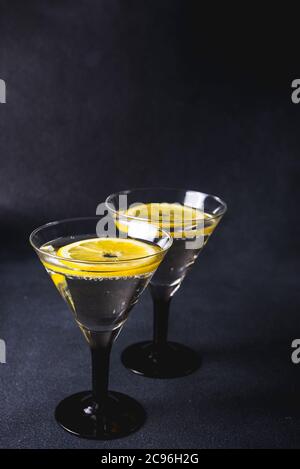 Alcohol cocktail with splash.Dry martini with black olives.Vermouth cocktail inside martini glass over dark background.Martini glasses are on the bar. Stock Photo