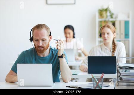 Group of operators sitting at the table with computers they working in call center Stock Photo