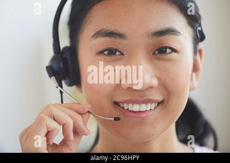 Close-up of Asian young operator in headphones smiling at camera Stock Photo