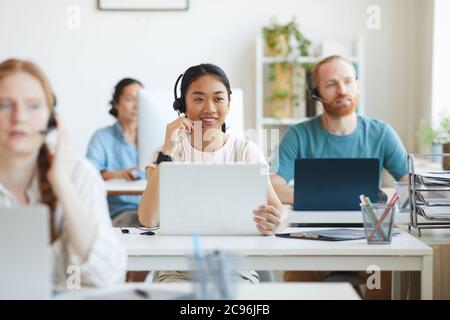 Group of operators sitting at their workplaces with computers and working in customer service call center Stock Photo